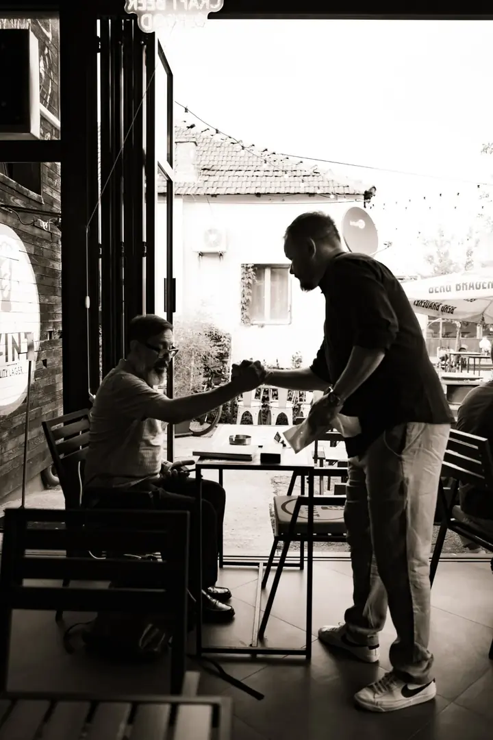 Nefiltrirano Beograd — rukovanje sa gostom, crno-bela fotografija sa događaja